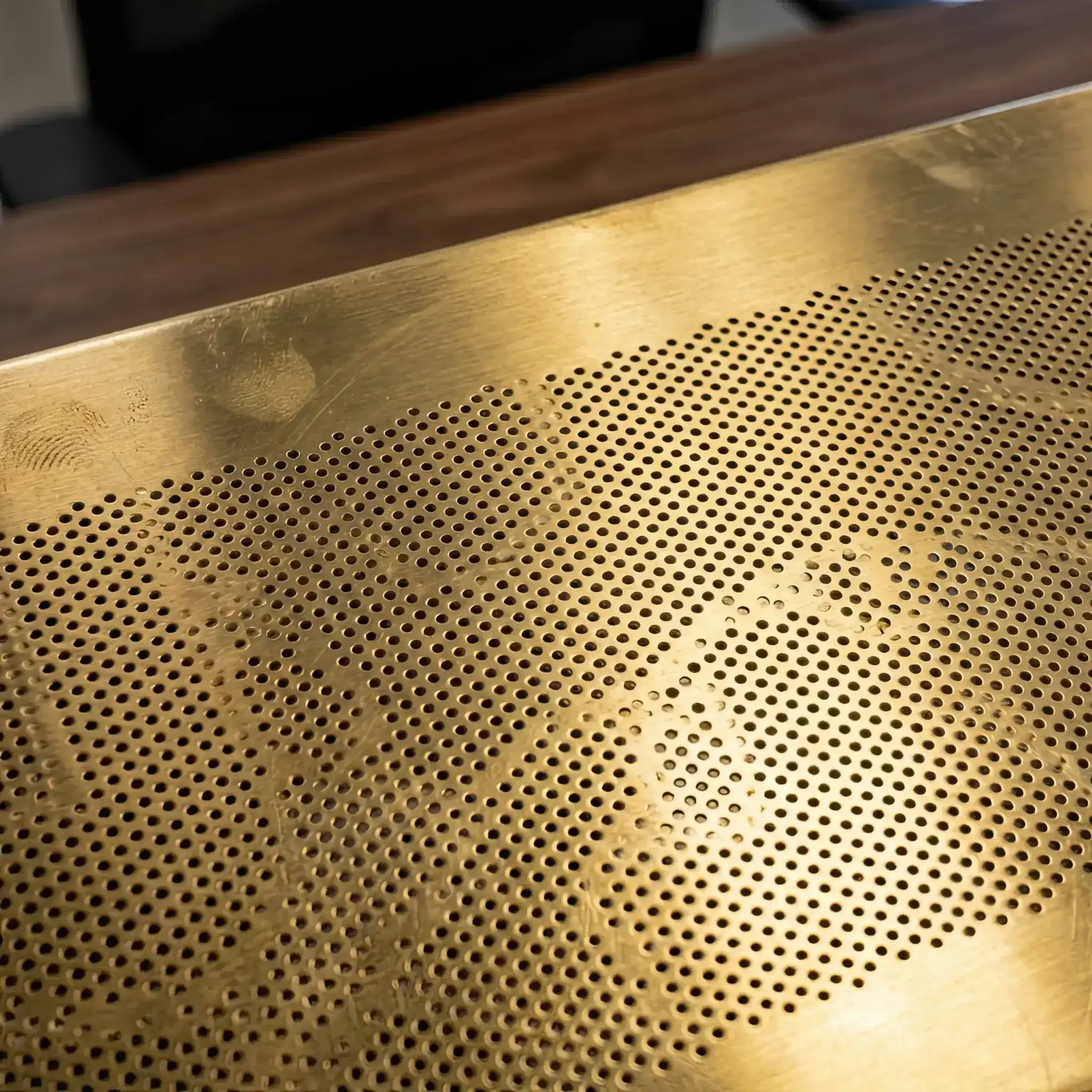 Interior detail: Macro shot of a micro-perforated brass panel with an acoustic layer